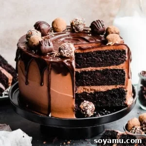 The sliced chocolate truffle cake topped with chocolate drip and truffles, with slices on plates.