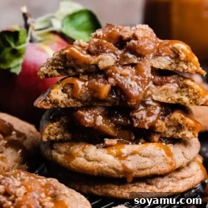 A stack of caramel apple pie cookies with a few broken in half to show the chewy cookies and apple filling.