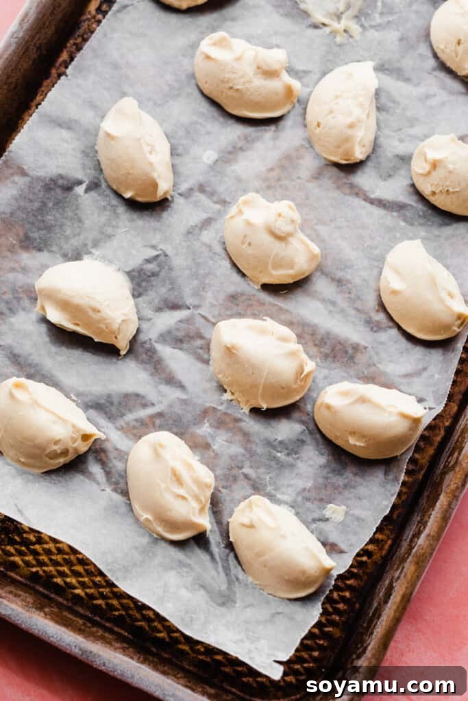 Irresistible Funfetti Cookies with a Cake Batter Cheesecake Surprise 6 Neatly formed dollops of frozen cheesecake filling, perfectly solid and ready for stuffing, arranged on a parchment-lined baking sheet.