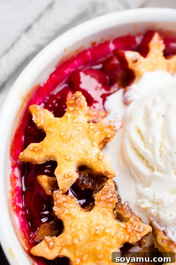 Close-up of a single cherry cobbler in a ramekin, showcasing the rich cherry filling and golden crust.