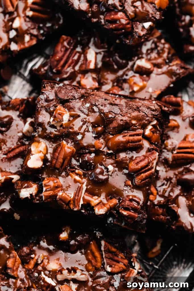 Irresistible Turtle Brownies 10 A close-up on a sliced turtle brownie topped with salted caramel sauce and pecans.