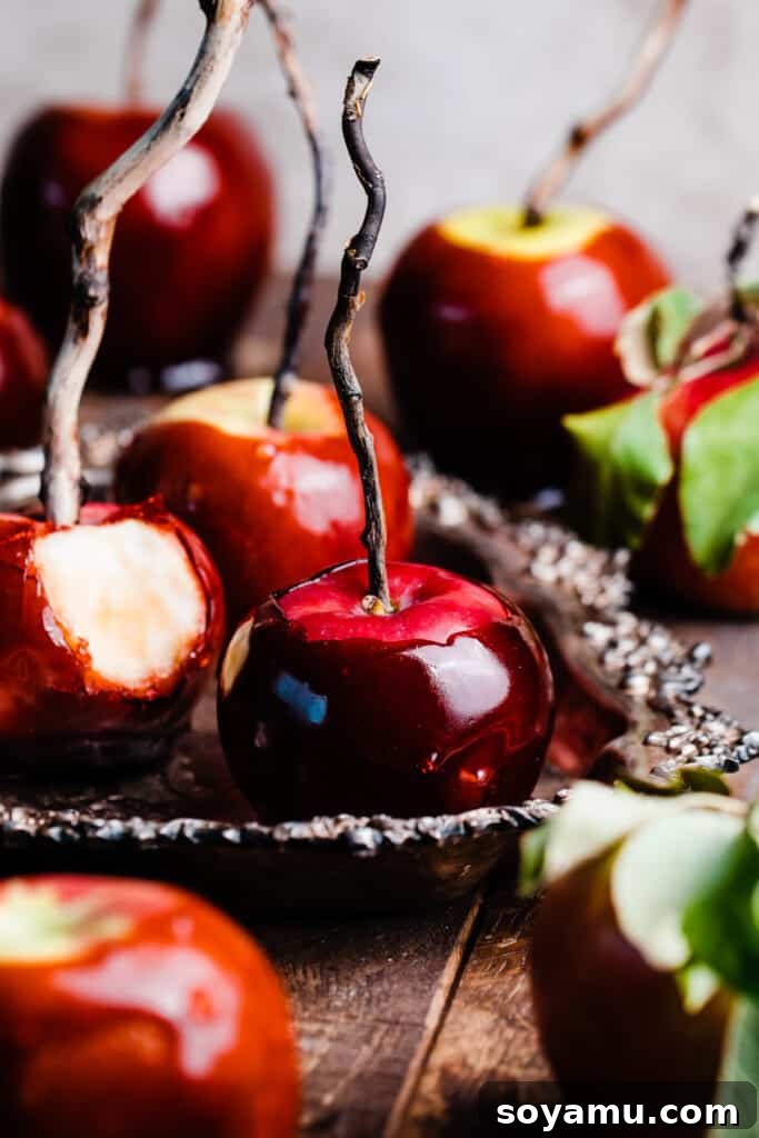 A collection of perfectly dipped, glossy candy apples resting on a rustic vintage serving tray, showcasing their hard, vibrant coating.