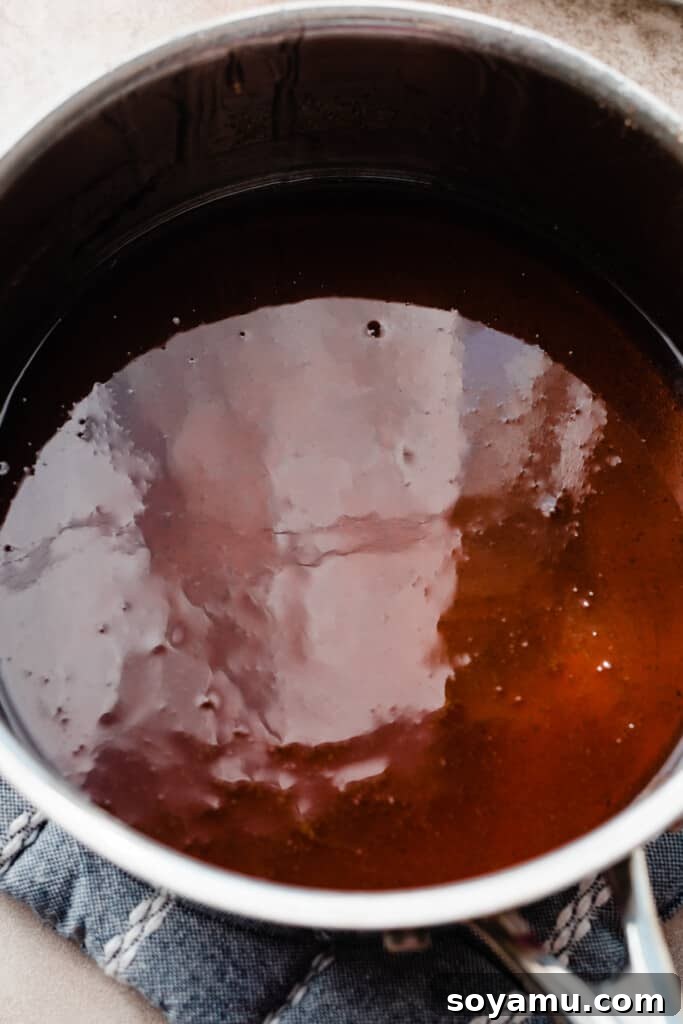 A pot of vibrant red sugar syrup resting off the heat, its surface smooth and free of bubbles, ready for dipping.