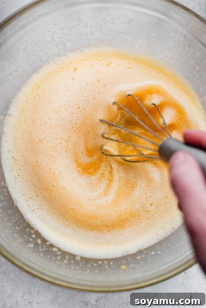 Ultra Fudgy Gluten Free Brownies 5 Eggs and sugar being whisked together in a bowl, showcasing the pale yellow, aerated mixture.