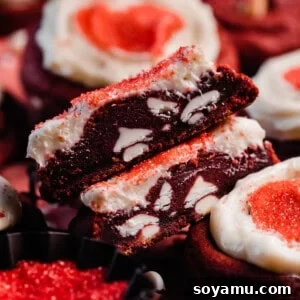 Two halves of a frosted red velvet cookie, showing the rich, fudgy insides and creamy frosting, indicating a perfect texture.