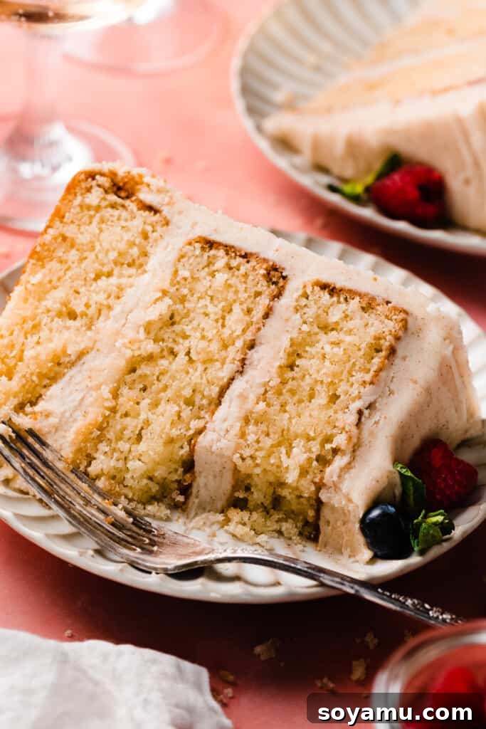 Decadent 8-inch Vanilla Cake with Golden Brown Butter Frosting 3 A close-up of a slice of vanilla cake on a plate, with a bite missing.