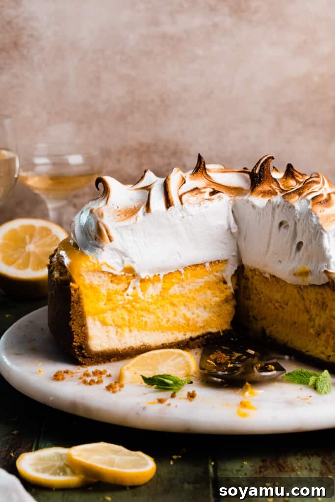 A close-up view of a sliced lemon meringue pie cheesecake, revealing its beautiful internal layers: the golden crust, the creamy lemon cheesecake, the vibrant lemon curd, and the impressive, fluffy meringue topping.