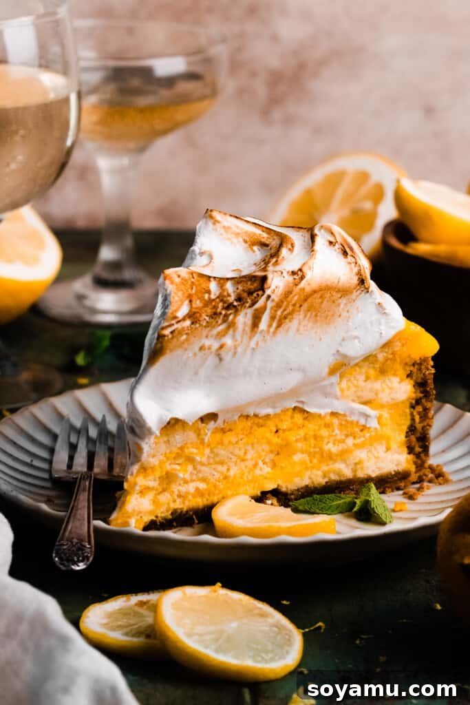 A stunning slice of the lemon meringue cheesecake presented on a decorative cake plate, highlighting the airy meringue and the creamy lemon filling.