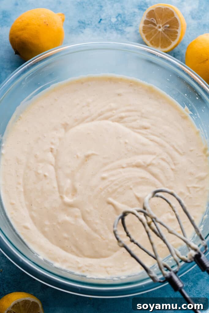 A large mixing bowl filled with smooth, pale yellow cheesecake batter, perfectly prepared for baking.