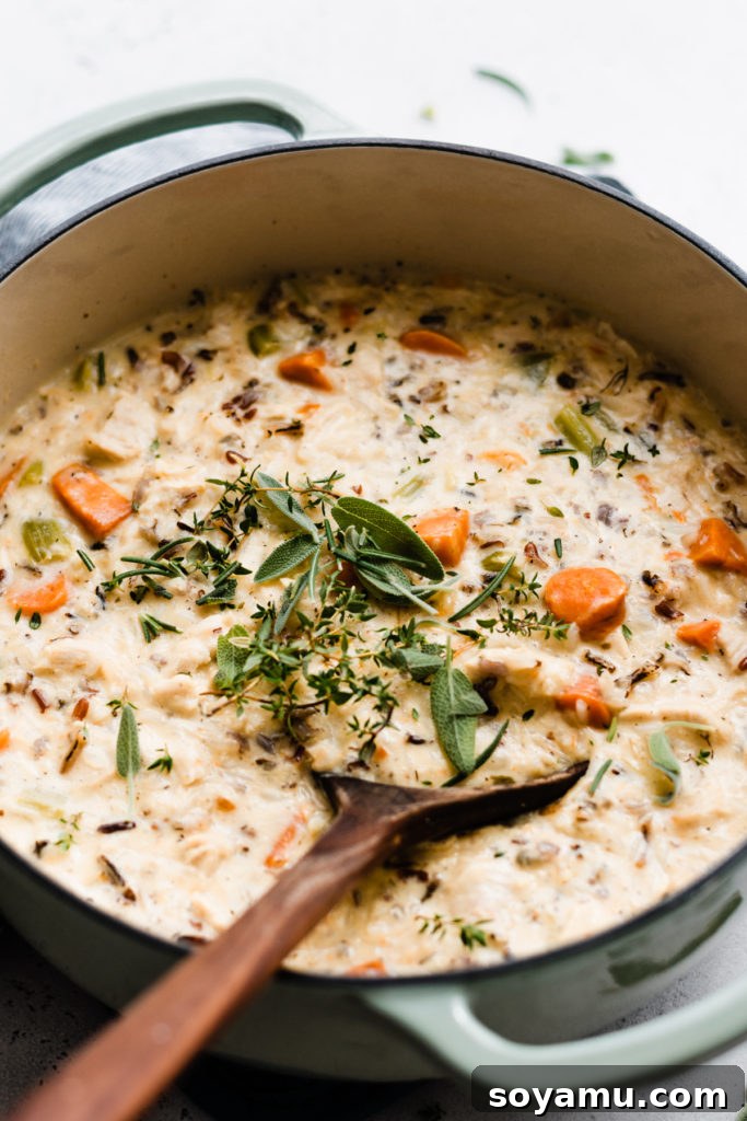 Soulful Chicken Wild Rice Soup 7 A close-up view of the rich, creamy chicken wild rice soup simmering in a rustic Dutch oven, highlighting the textures of chicken, rice, and vegetables.