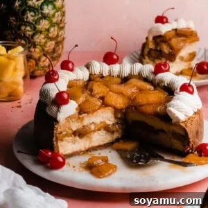 The sliced open pineapple cheesecake on a cake platter, topped with caramelized pineapple, whipped cream, and cherries.