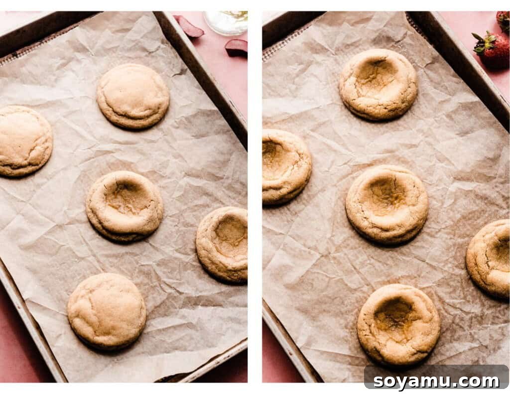 Freshly baked cookies on a baking sheet, some already indented and shaped, others waiting for their turn.