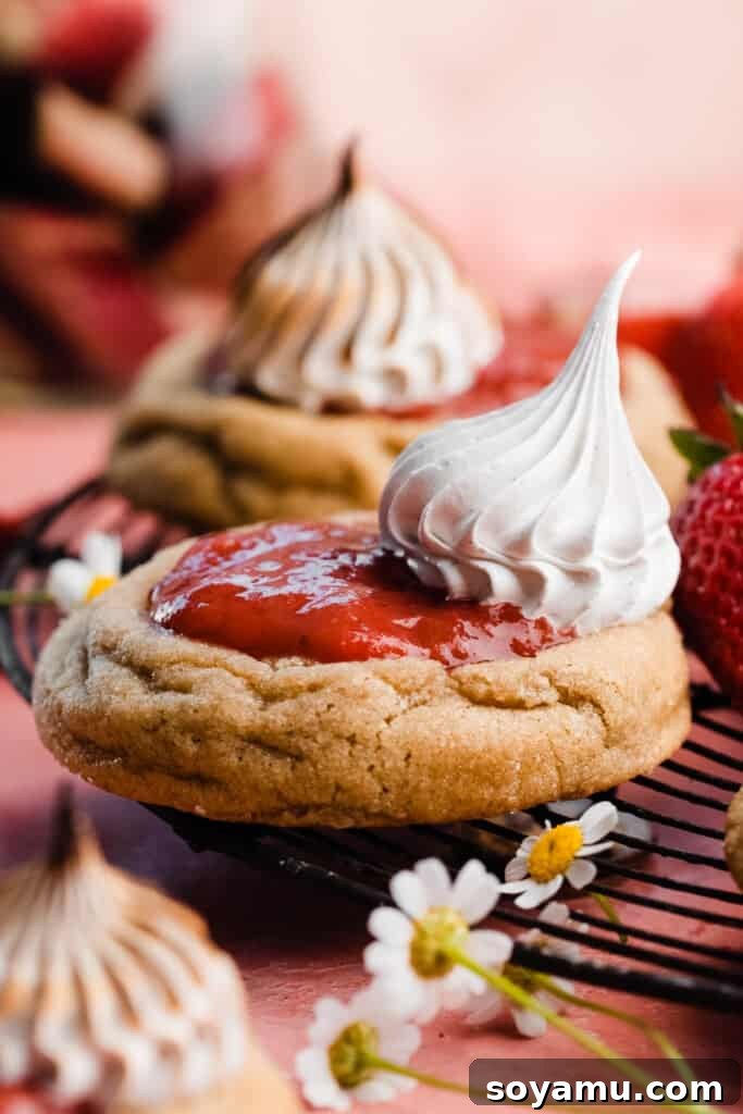 A close-up of a finished strawberry rhubarb cookie, showcasing a tall, stiff dollop of perfectly piped and toasted meringue.