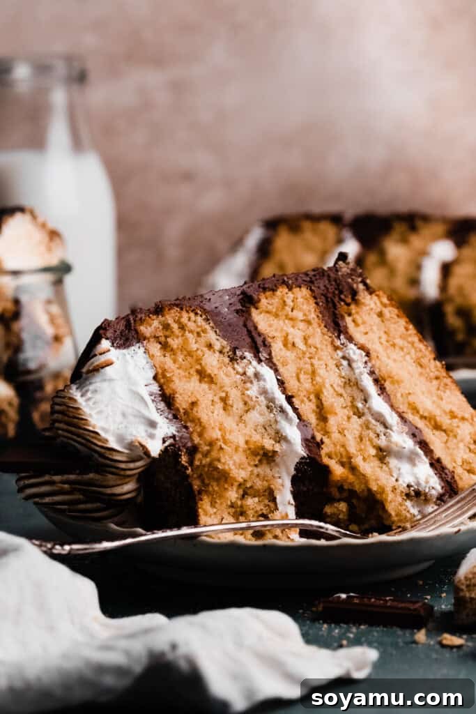 A slice of s'mores cake on a plate, with a bite missing.