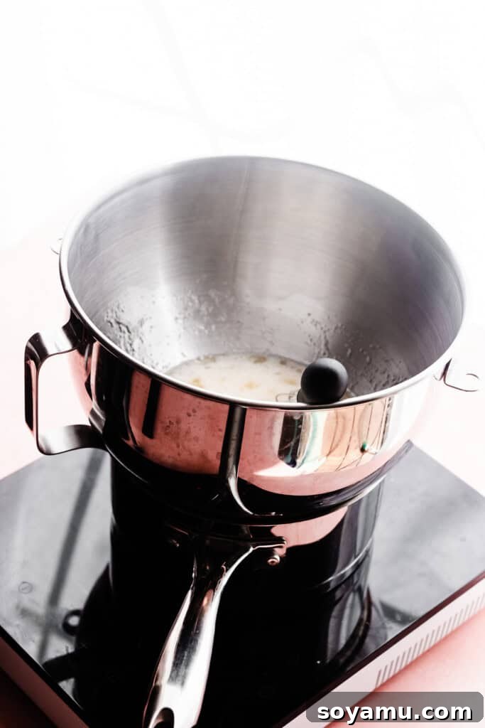 Crafting Silky Smooth Swiss Meringue 4 A gleaming metal mixing bowl perfectly positioned atop a small saucepan, ready for the double boiler method.