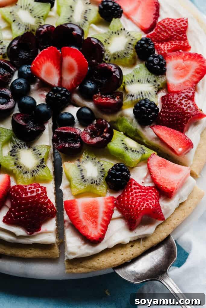 A close-up image showing a cake lifter expertly removing a perfectly cut slice of Fruit Pizza from a large, decorated platter, ready to be served.