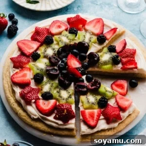 The sliced fruit pizza on a marble platter.