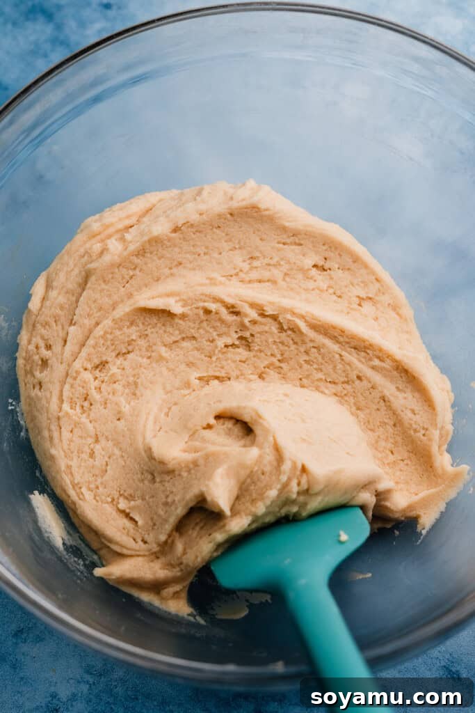 A bowl filled with the freshly prepared, soft, and slightly golden sugar cookie dough, ready for chilling and shaping.