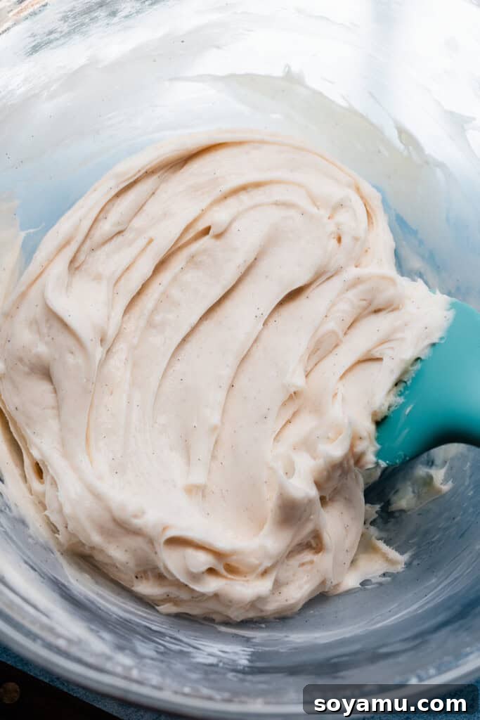 A bowl brimming with a smooth, fluffy, and tangy cream cheese frosting, perfectly whipped and ready to be spread onto the cooled sugar cookie crust.