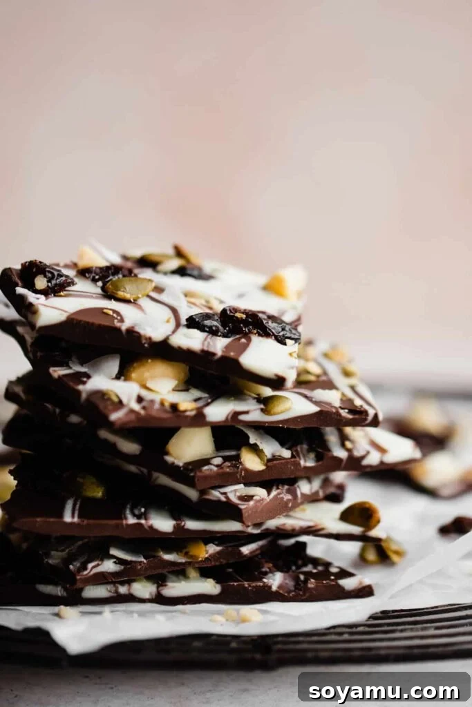 Easy Five-Ingredient Homemade Chocolate Bark 2 A stack of chocolate bark pieces, with swirls of white and semi-sweet chocolate, topped with various delicious ingredients.