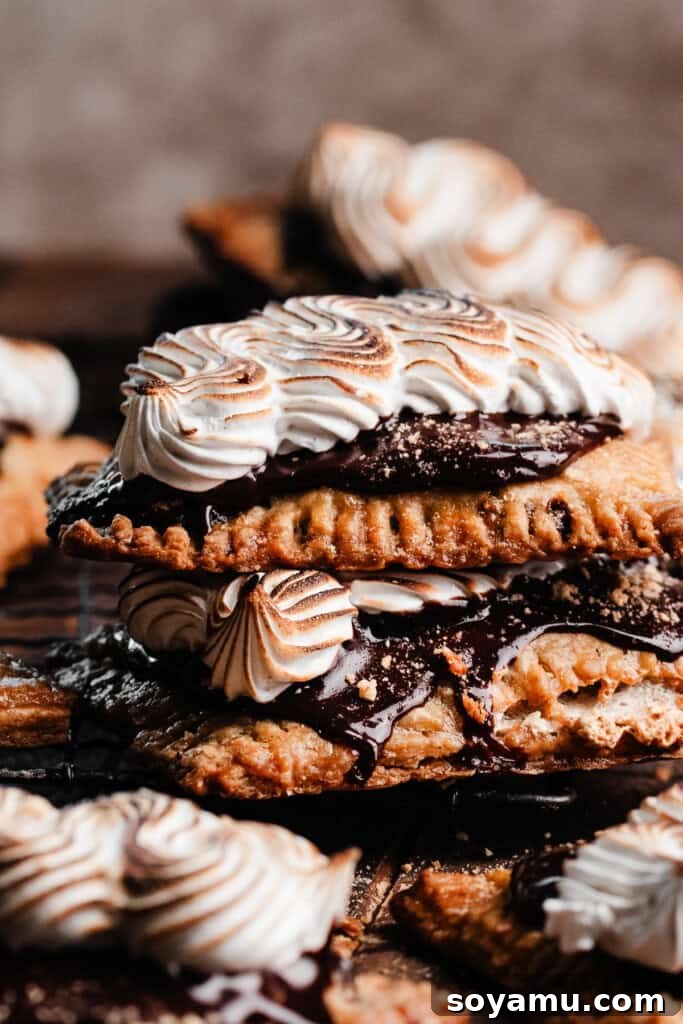 A stack of s'mores pop tarts covered in chocolate fudge icing and swirls of toasted marshmallow topping, ready to be enjoyed.