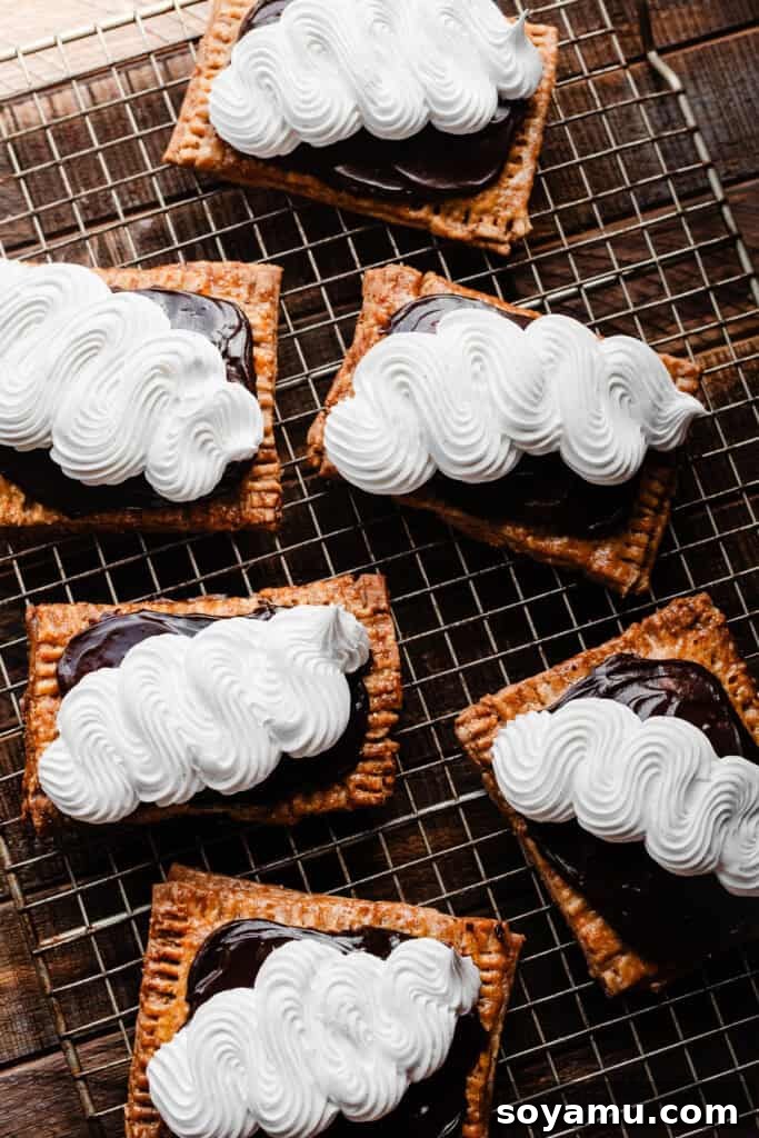The iced and marshmallow piped s'mores pop tarts cooling on a rack, garnished with graham cracker crumbs.