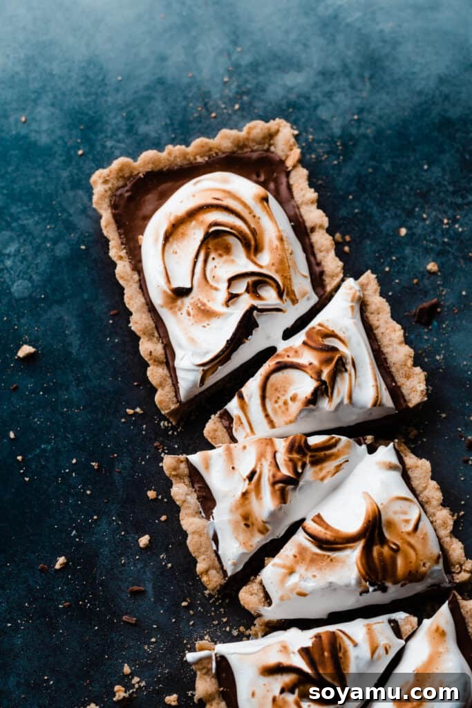 Gourmet S'mores Tart with Torched Meringue 11 A close-up shot of individual S'mores Tart slices on a blue surface, highlighting the layered perfection.