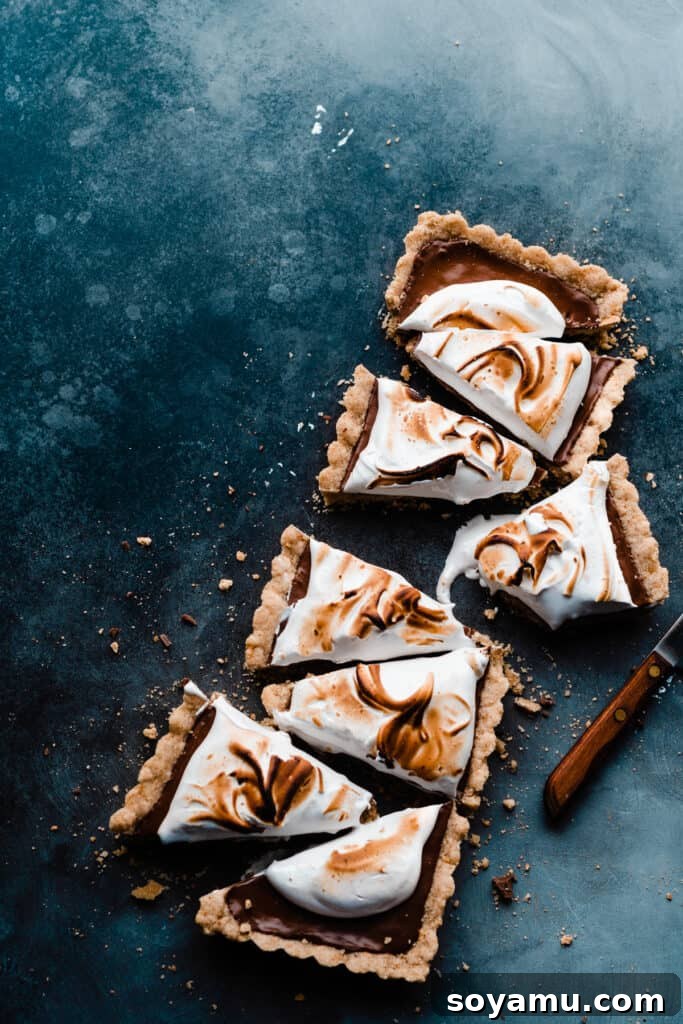 Gourmet S'mores Tart with Torched Meringue 3 A S'mores Tart, elegantly sliced into portions, displayed on a contrasting blue surface.