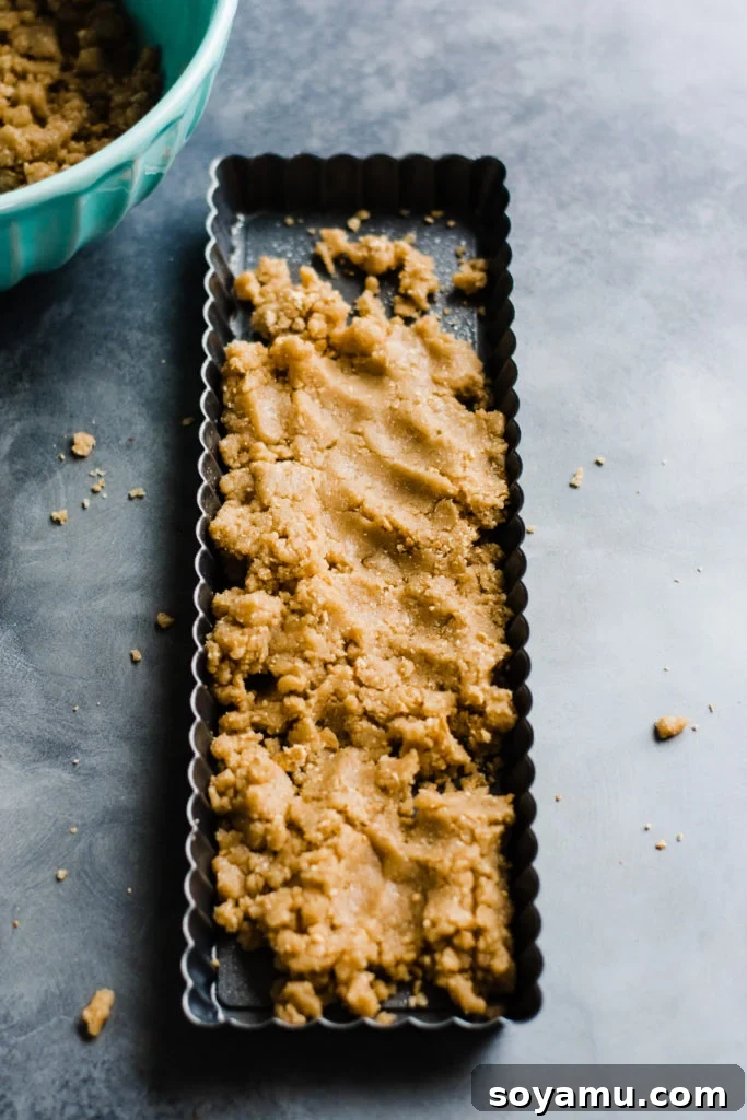 Gourmet S'mores Tart with Torched Meringue 4 A tart pan, perfectly filled with the rich, graham cracker-infused cookie dough, ready for baking.