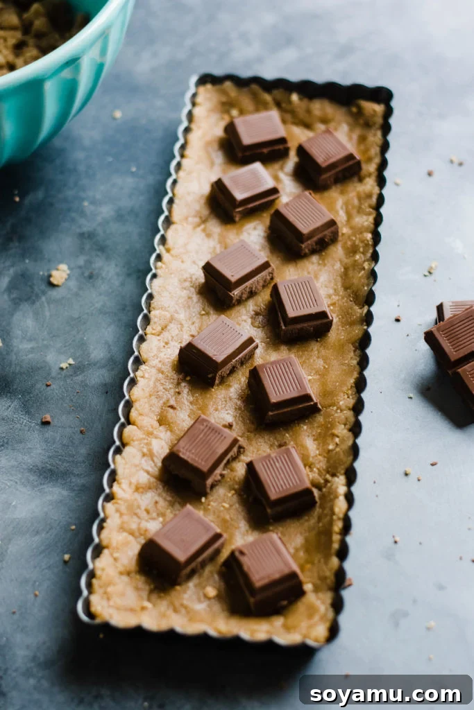 Gourmet S'mores Tart with Torched Meringue 5 An unbaked tart crust, neatly pressed into the pan, topped with pieces of milk chocolate bars, ready for the oven.
