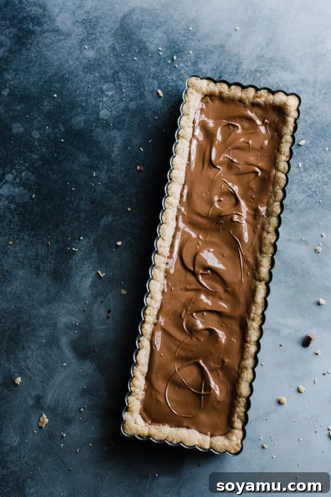 Gourmet S'mores Tart with Torched Meringue 6 The freshly baked S'mores Tart crust, now adorned with a perfectly melted and smoothly spread milk chocolate layer.