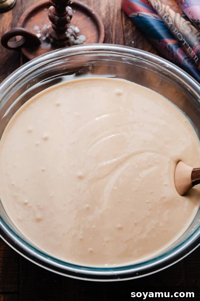 Whimsical Butterbrew Cheesecake 6 A bowl of creamy, light brown cheesecake batter, smooth and ready to be poured into the crust. Small swirls of butterscotch are visible.