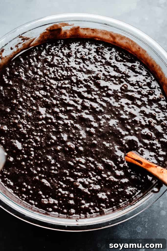 A large mixing bowl filled with rich, dark chocolate cake batter, smooth and gleaming, made with black cocoa powder for an intensely deep color and flavor, ready for baking.
