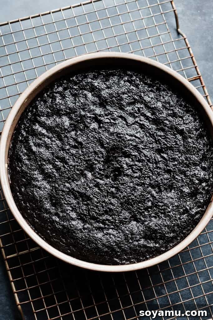 A perfectly baked, dark chocolate cake layer cooling on a wire rack after being removed from the oven, its deep color and even texture ready for the next step of frosting and assembly.