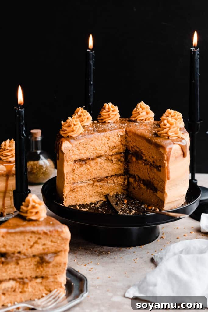 Whip Up 10-Minute Golden Butterscotch 8 Layered butterscotch cake with a cross section missing, on a black cake stand with a butterscotch drip and frosting swirls on top.