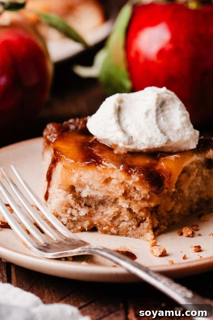 Sticky Apple Caramel Cake 3 A close-up view of a single slice of caramel apple upside down cake, showing the distinct layers of cake, caramelized apples, and crumb topping.