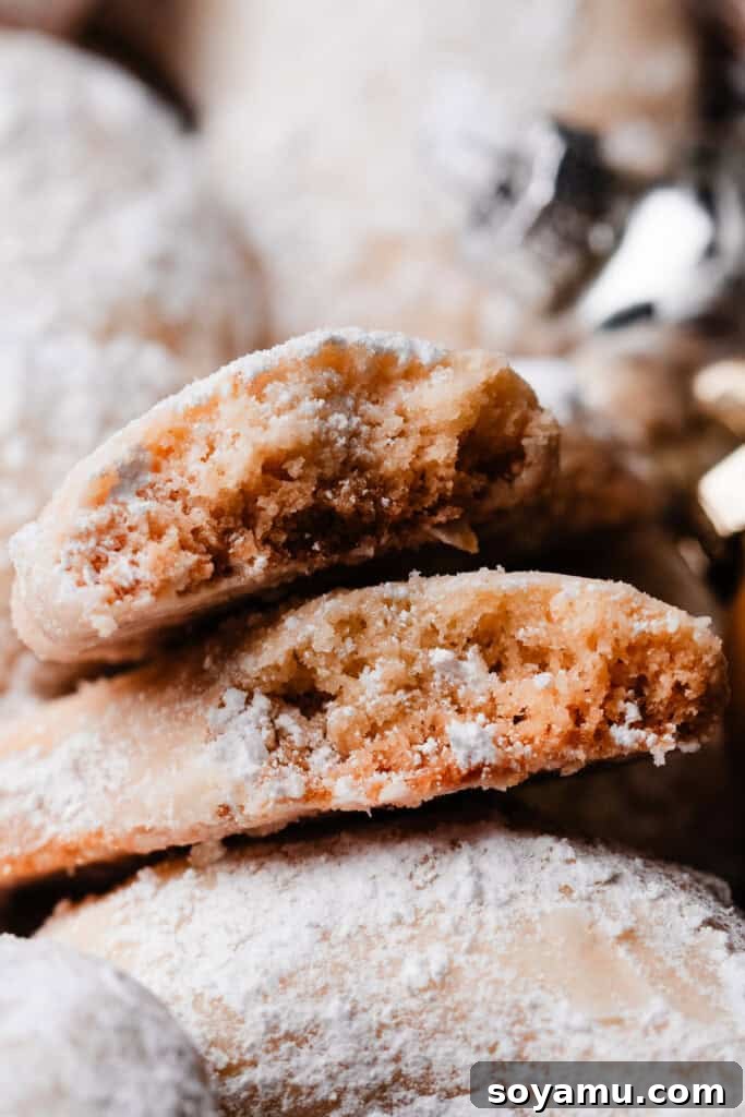 Sweet Almond Moons 3 A close-up view of two halves of an Almond Crescent cookie, showcasing its delicate, crumbly texture and fine dusting of powdered sugar inside.