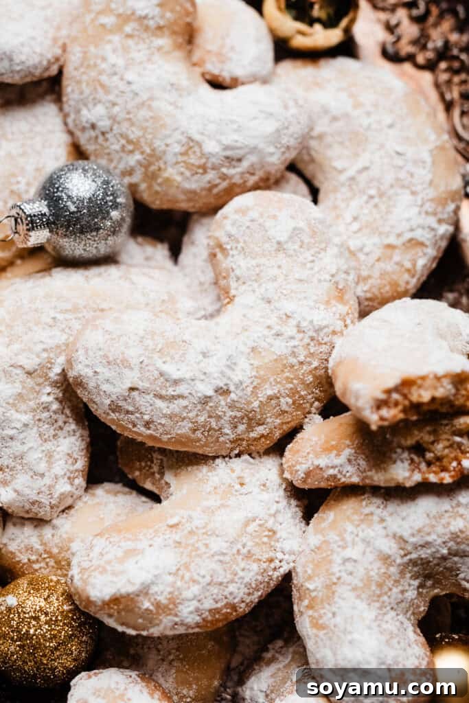Sweet Almond Moons 8 Freshly baked Almond Crescent cookies being dusted generously with powdered sugar in a bowl.