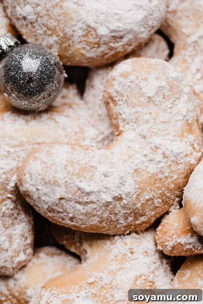 Sweet Almond Moons 9 A close-up on a perfectly powdered sugar dusted almond cookie, showcasing its delicate texture.