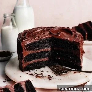 The sliced chocolate cake on a marble cake plate, with glasses of milk and slices of cake on plates nearby.
