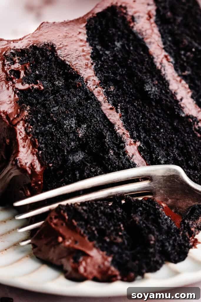 Ultimate Eggless Chocolate Fudge Cake 3 A close-up shot of a fork digging into a decadent slice of eggless chocolate cake, highlighting its moist and tender interior.