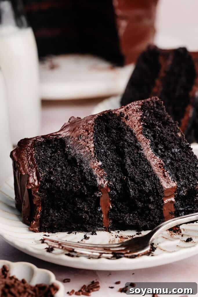 Ultimate Eggless Chocolate Fudge Cake 10 A thick, enticing slice of eggless chocolate cake resting on a plate, with a few bites already taken, revealing its irresistible texture.