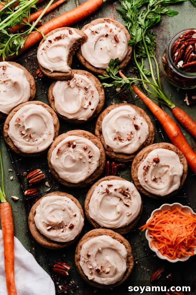 Spiced Carrot Cake Cookies with Brown Butter Cream Cheese 3 Frosted carrot cake cookies arranged beautifully on a rustic green wooden surface.