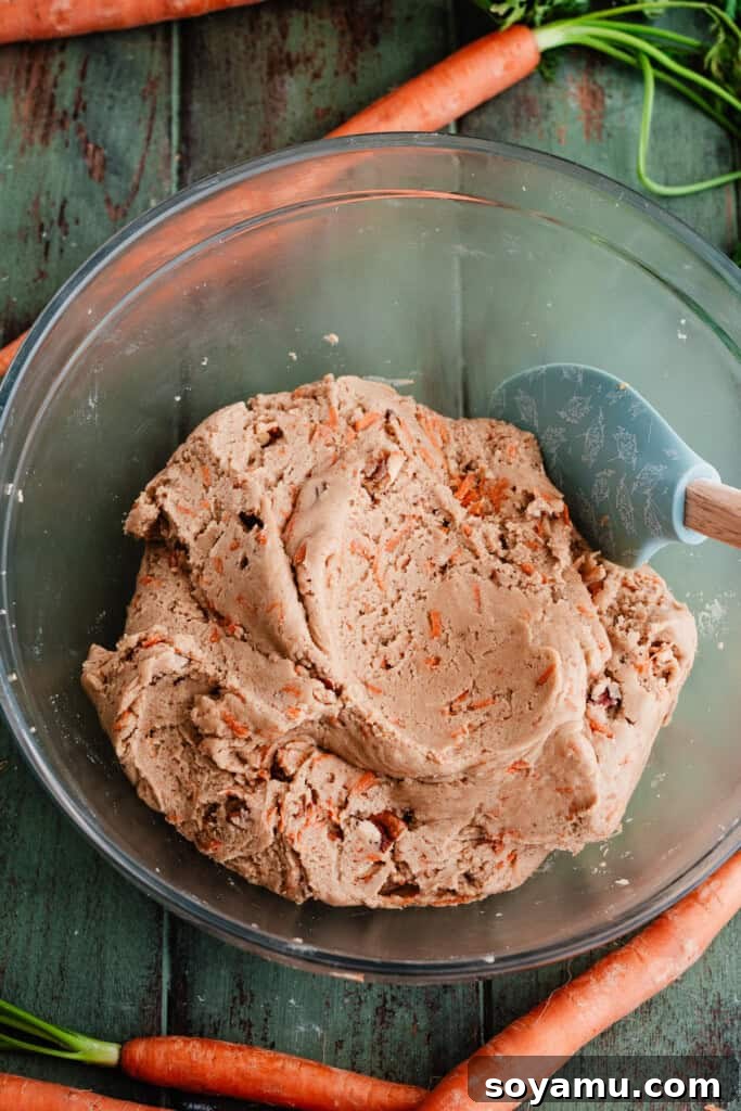 Spiced Carrot Cake Cookies with Brown Butter Cream Cheese 5 A large mixing bowl filled with freshly prepared carrot cake cookie dough, studded with grated carrots and pecans.