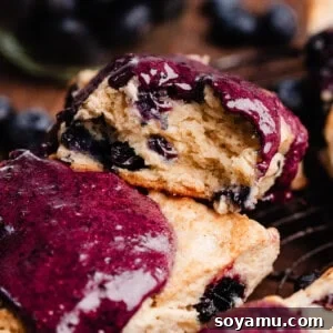 A close-up on a blueberry glazed scone with a bite missing, showing the tender, flaky layers inside.
