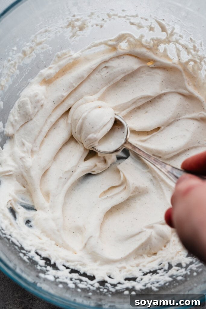 Whip Up Perfect Homemade Cream 10 A spoon being pushed vertically through whipped cream waves, forming an elegant dollop.