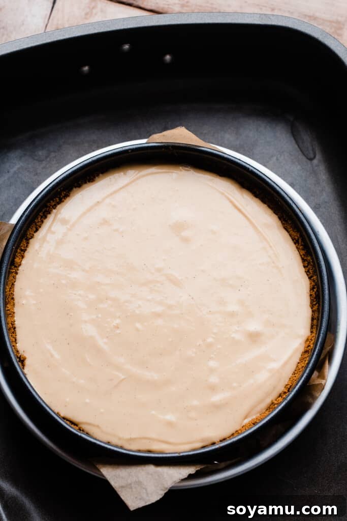 Velvety Rich New York Cheesecake Masterpiece 12 The cheesecake springform pan placed inside a 10-inch cake pan, which then sits inside a larger roasting pan, prepared for a leak-proof water bath.