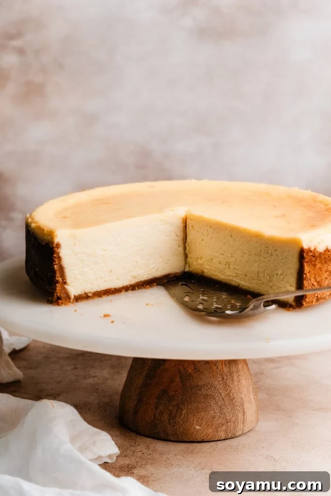 Velvety Rich New York Cheesecake Masterpiece 4 A whole New York Style Cheesecake, perfectly sliced, displayed on an elegant cake stand.
