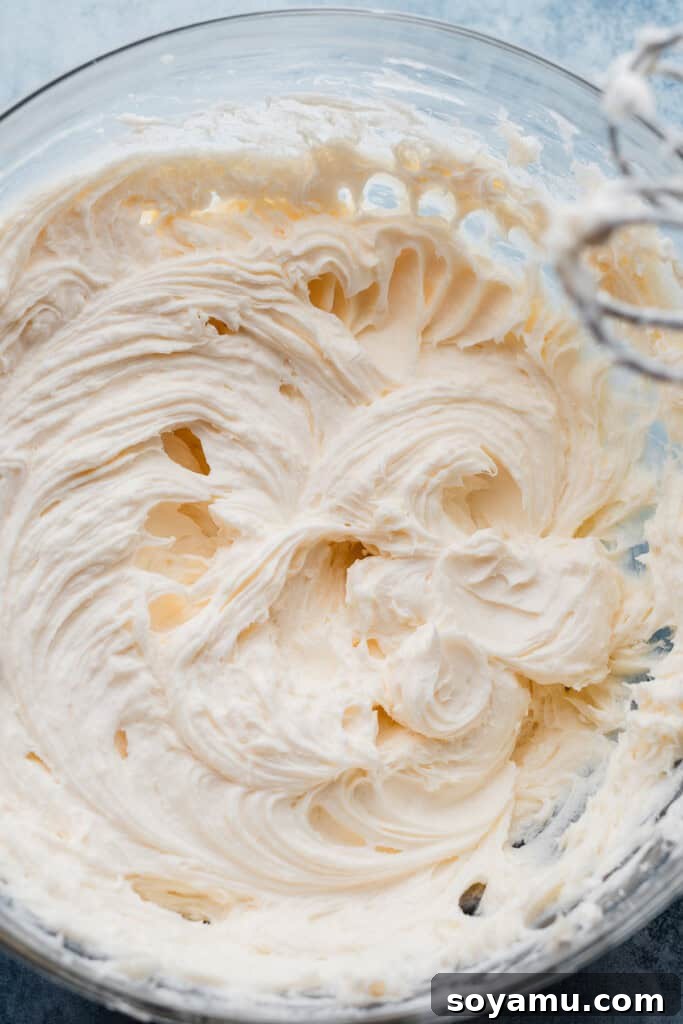 Velvety Rich New York Cheesecake Masterpiece 6 A bowl showcasing the velvety smooth, creamed cream cheese, perfectly prepared as the base for the cheesecake filling.
