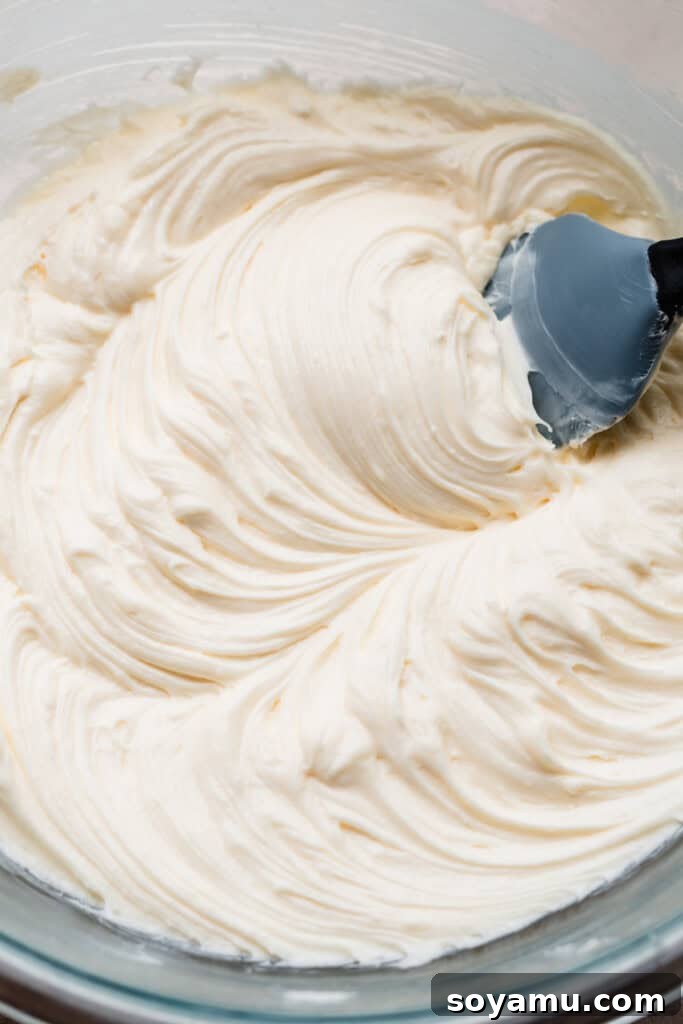 Velvety Rich New York Cheesecake Masterpiece 7 A close-up of the creamed cream cheese after granulated sugar has been added and thoroughly mixed, creating a smooth, light batter.